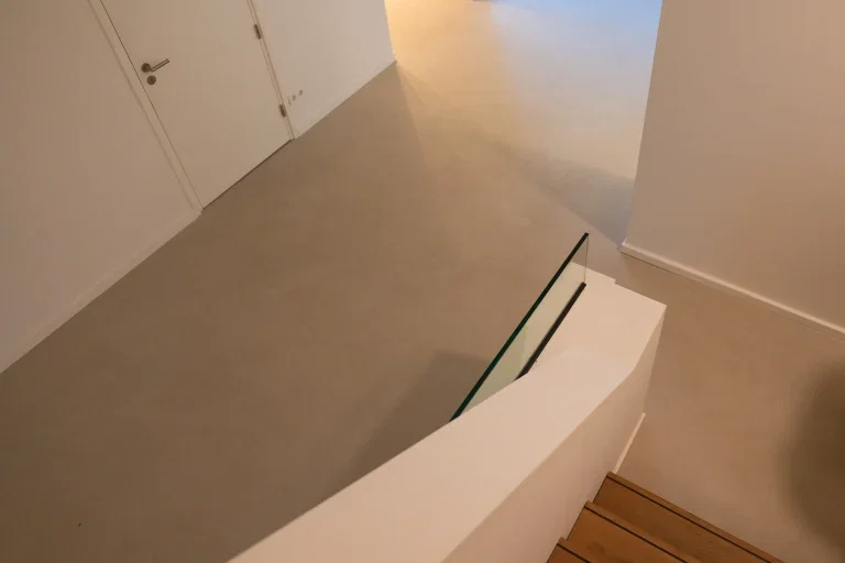 Lavasteen kleuren — Lavasteen prijs — Lavasteen gietvloer naadloos modern interieur — matte gietvloer in woning met glazen leuning