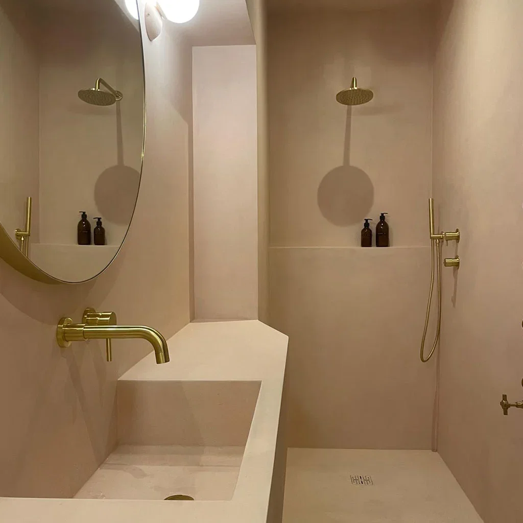Microcement badkamer met gouden kranen — waterdicht en voegvrij