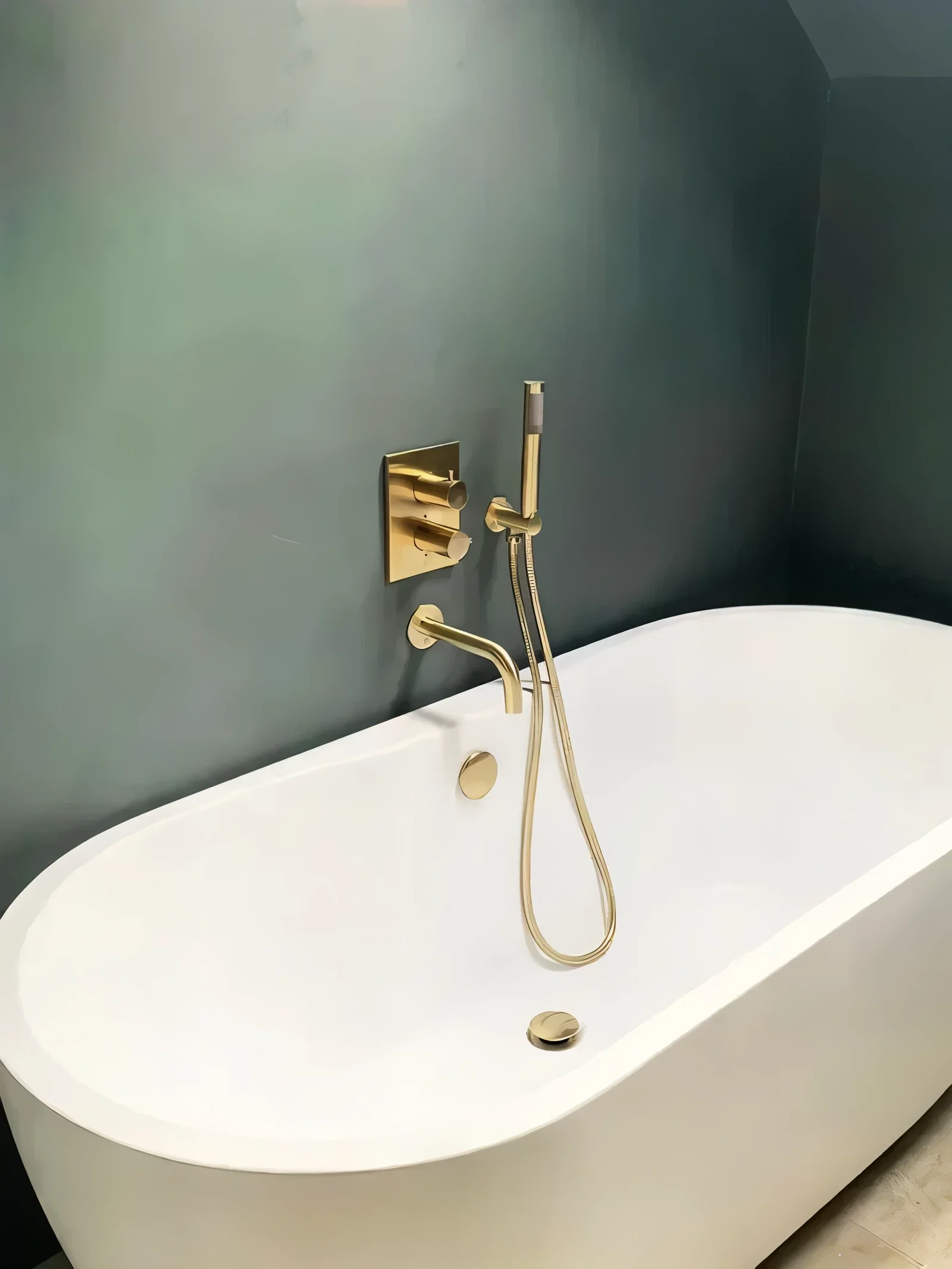 Microcement badkamerwand met gouden kraan en vrijstaand bad - betonlook wandafwerking
