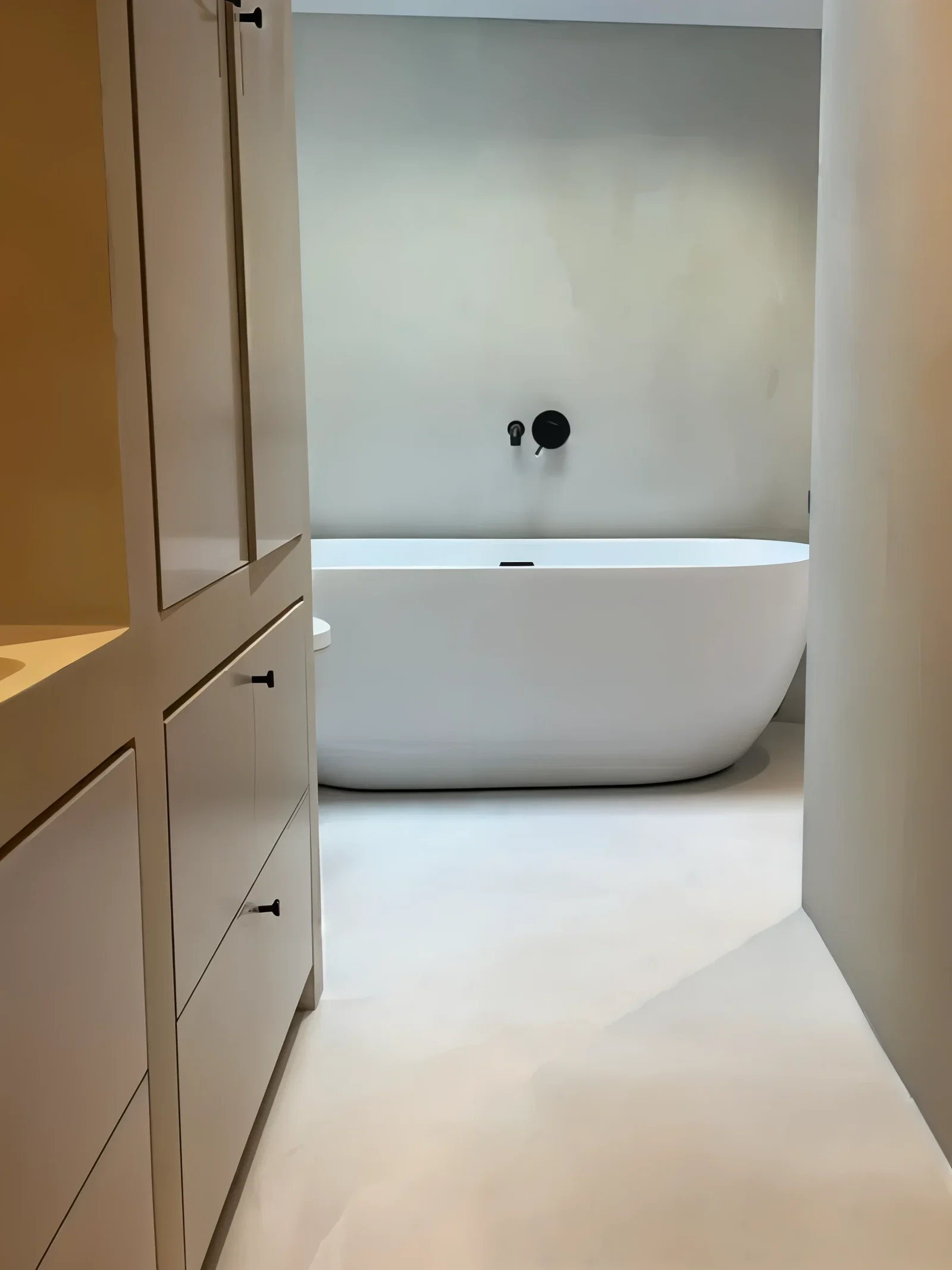 Naadloze microcement badkamer met vrijstaand bad en zwarte kraan