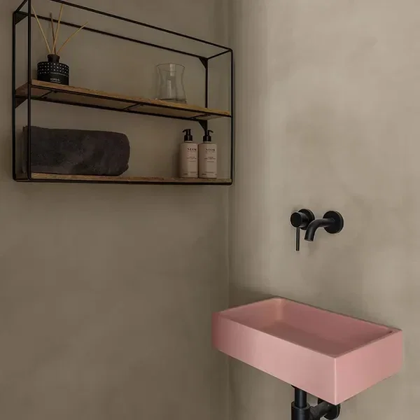 Microcement wastafel met roze waskom tegen naadloze microcement wanden