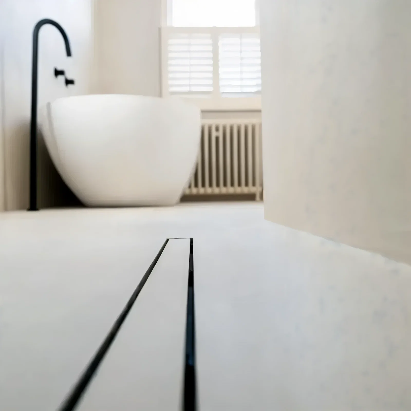 Naadloze witte microcement badkamervloer met lijnafvoer en antislip sealen en oplevering