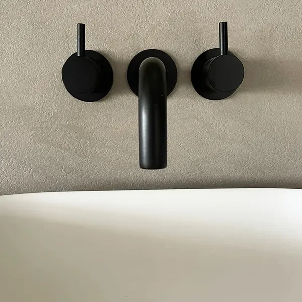 Microcement badkamer met zwarte kraan en naadloze wand