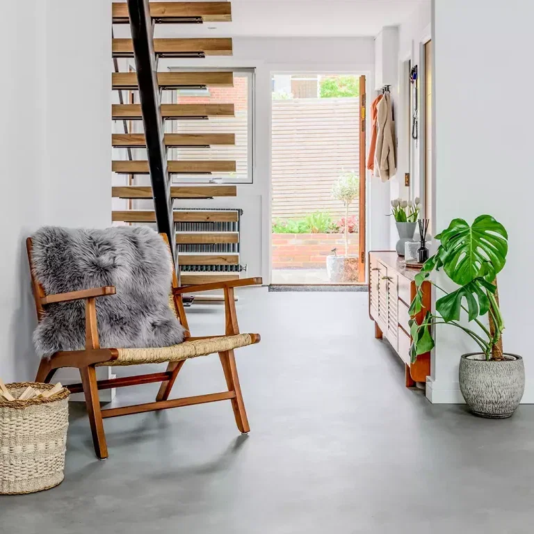 Grijze microcement vloer in hal met trap en plantendecoratie