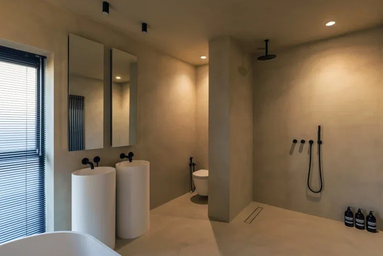 Naadloze microcement badkamer met wastafels, douche en voegvrije wanden