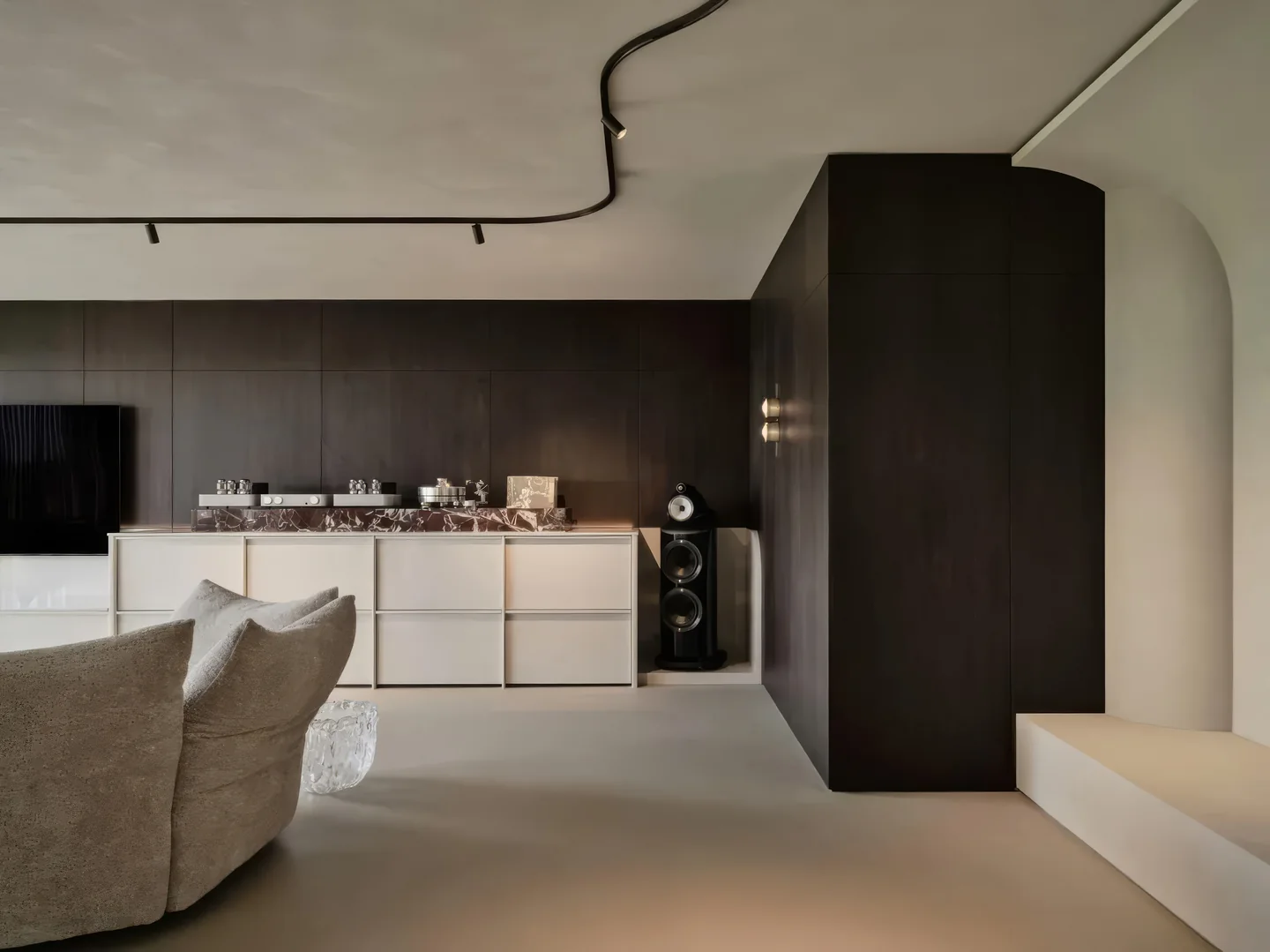Minimalistische woonkamer met naadloze microcement vloer en plafond, donkere houten wandpanelen — Microcement Studio