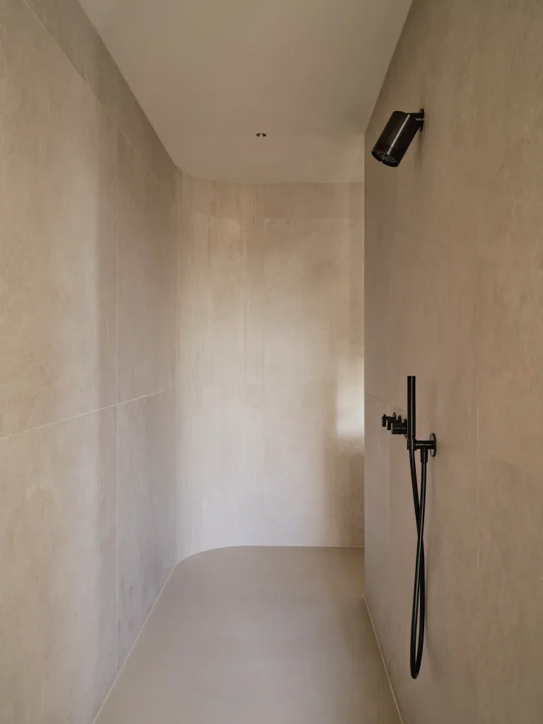 Inloopdouche met naadloze microcement wanden en vloer in beige met zwarte kraan
